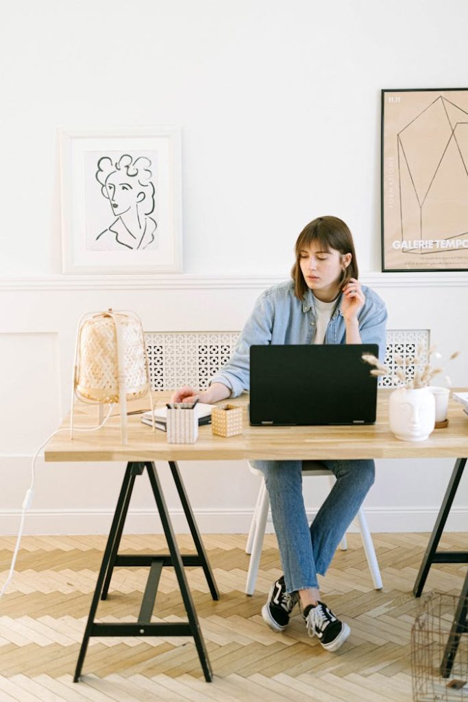 Stylish woman working on a laptop in a bright, modern home office interior.